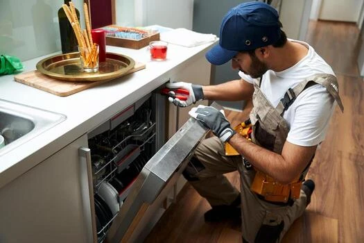 Technician using a screwdriver on an open dishwasher door