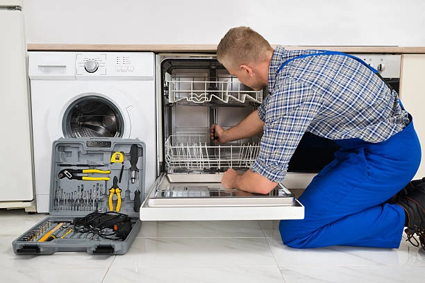 Technician inspecting a dishwasher interior next to a washing machine