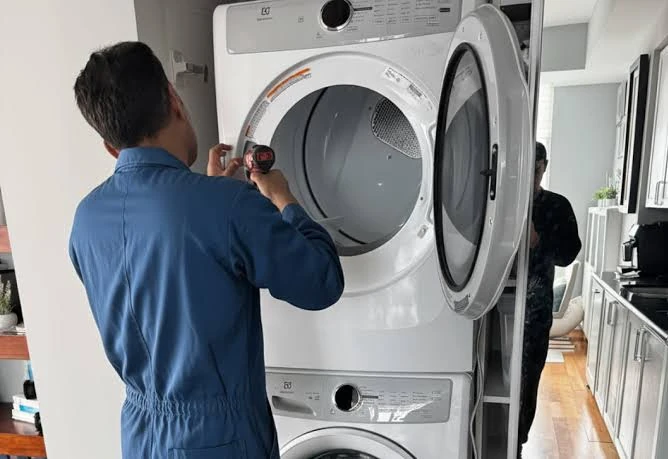 Technician servicing a stacked front-loading dryer