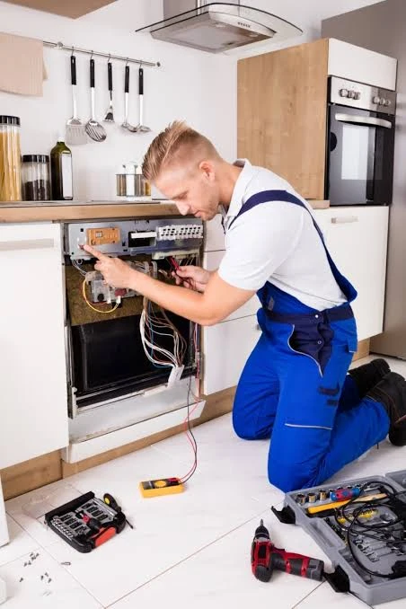 Technician checking an open dishwasher control panel with diagnostic tools