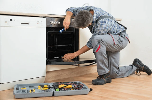 Technician inspecting the interior of an oven with a toolkit nearby